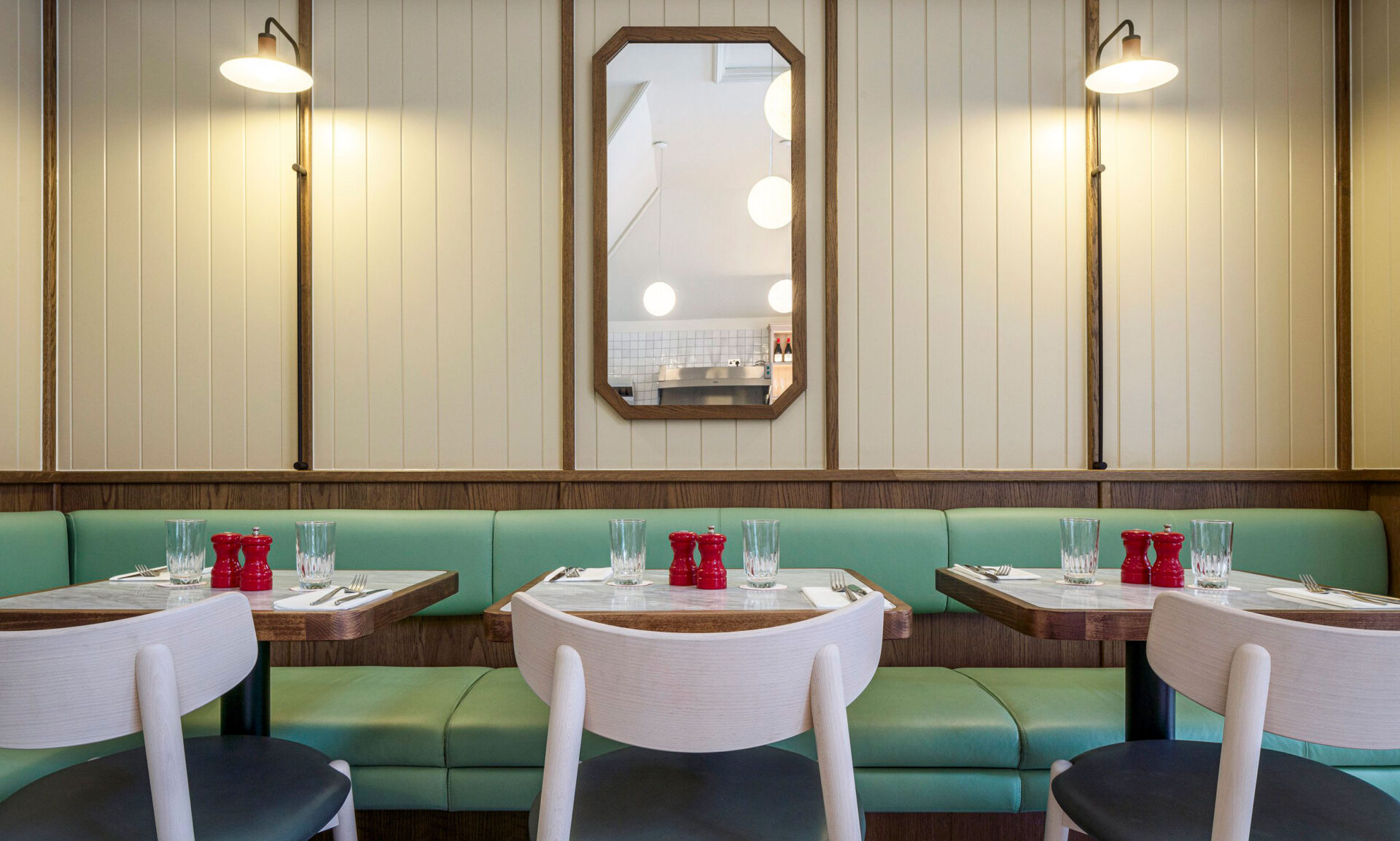Dining seating interior featuring mint green banquette, white wooden chairs and marble wood tables, inside Audrey's Cafe & Bar Borough modern and retro restaurant designed by 3Stories Interior Design and branding creative agency London