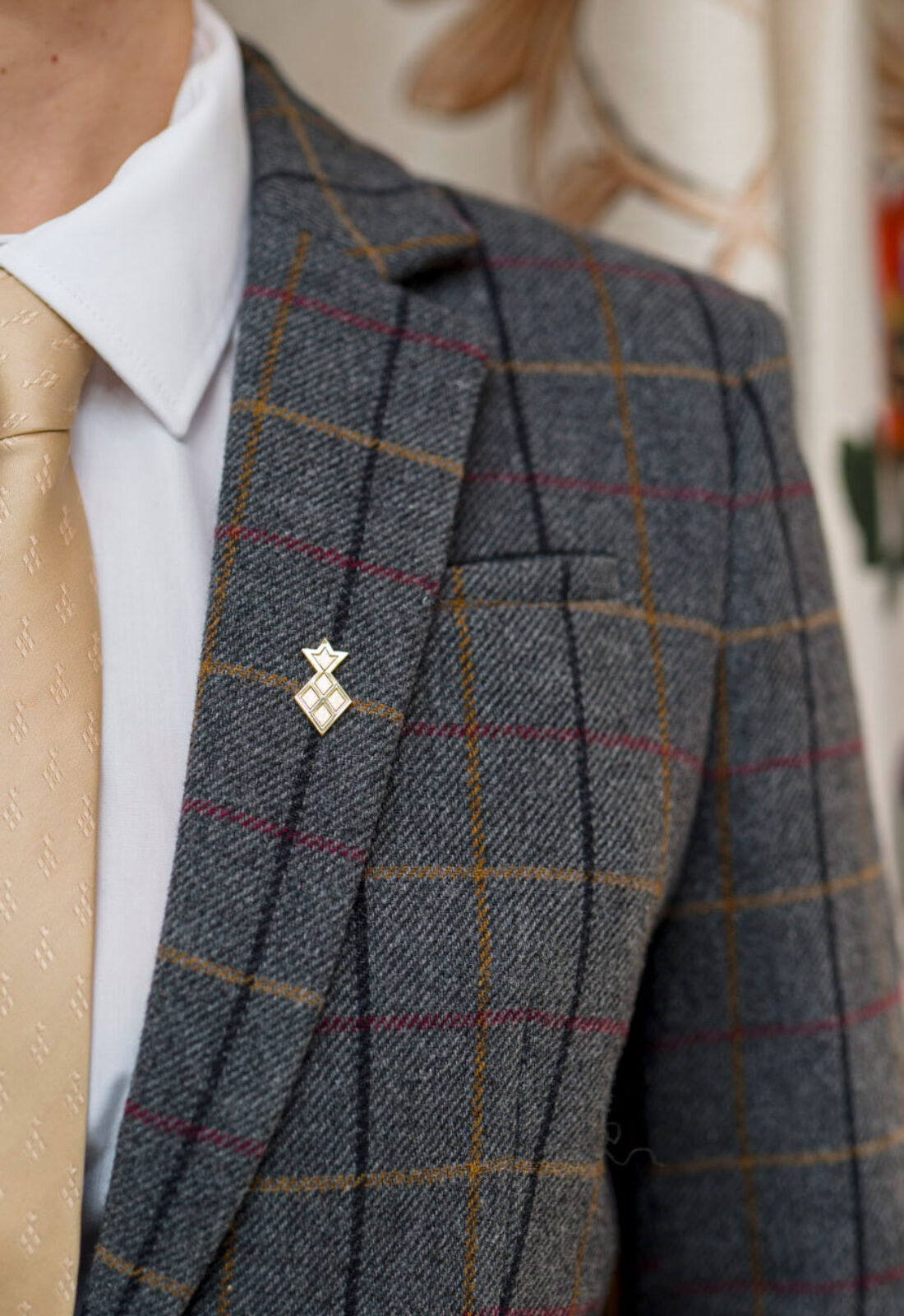 Uniform featuring branded custom lapel pin, tie and tartan smart jacket designed by 3Stories Interior Design and Branding creative agency for Roast Restaurant London